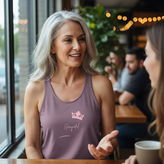 Woman in a purple tank top with a logo and text, sitting at a table in a casual setting.